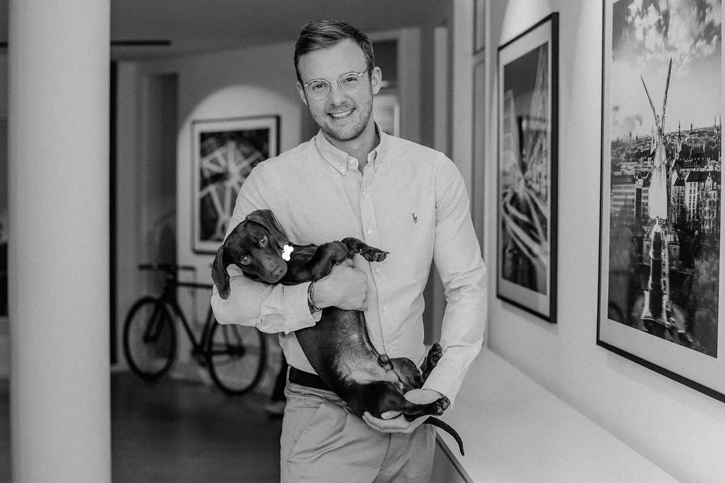 CEO und Gründer von BrainTalents Manuel Huhmann schaut lachend in die Kamera und hält Hund auf dem Arm. 